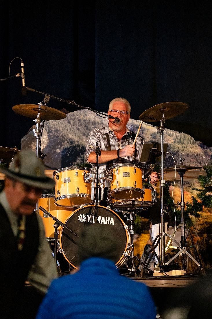 John Gunther singing and playing drums on stage, behind the band's yellow Yamaha kit