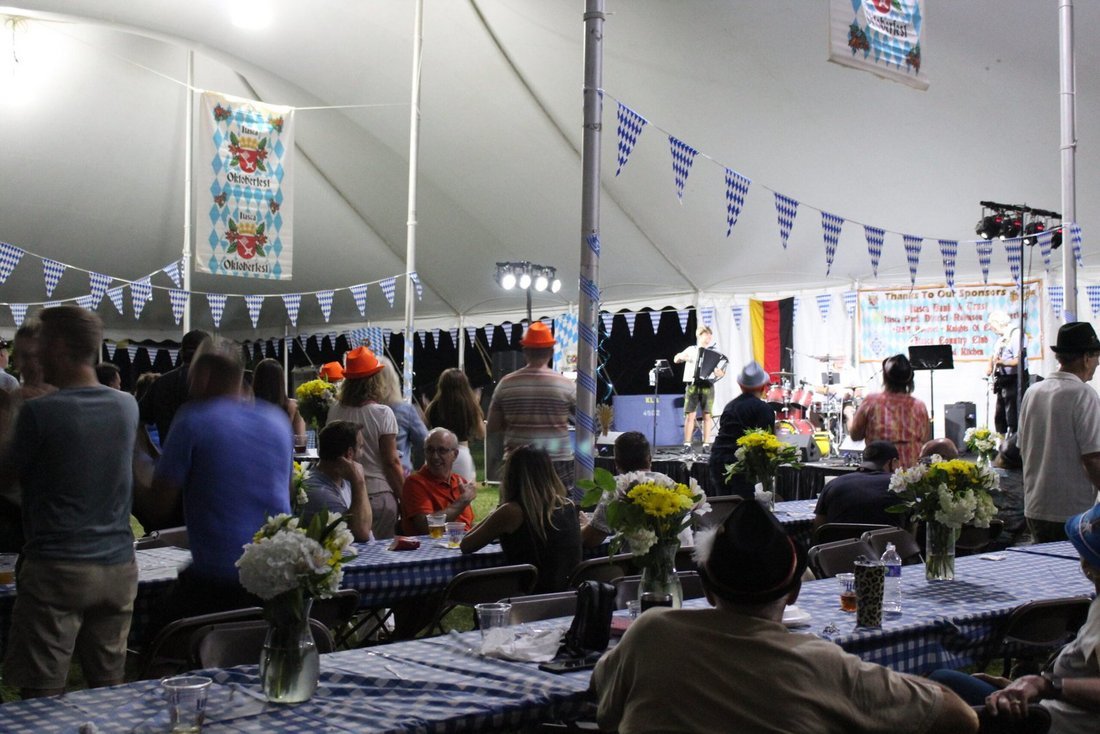 A full Oktoberfest tent in the evening, with the band on stage at the far end